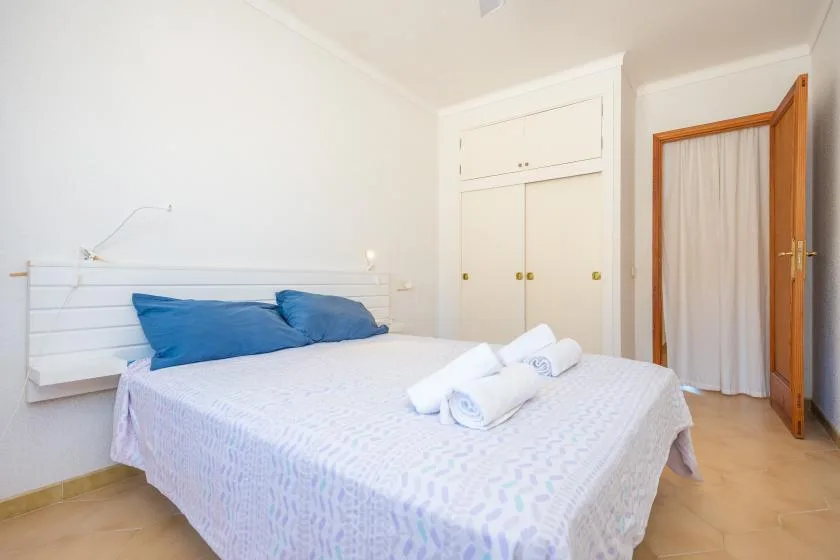 A bedroom with a bed, blue pillows, and folded towels.