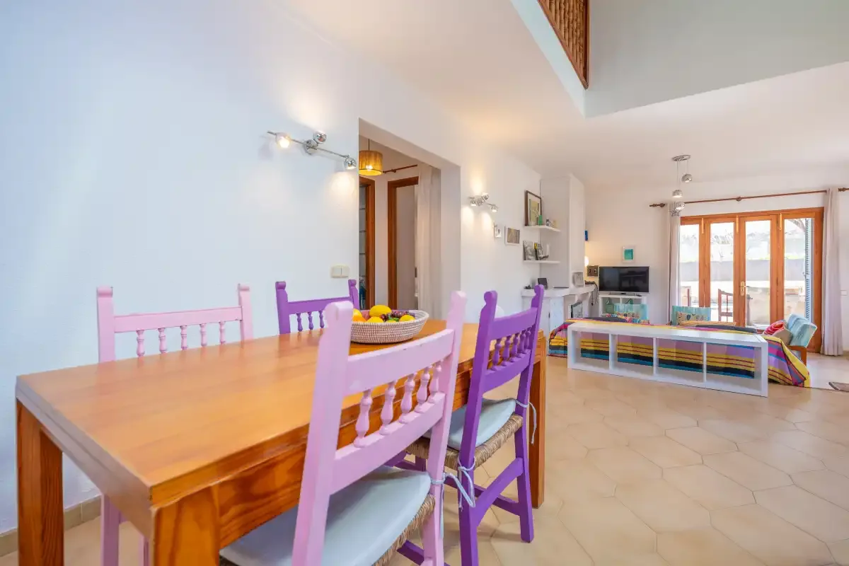 A bright open-plan living and dining area with colorful seating and a wooden table.
