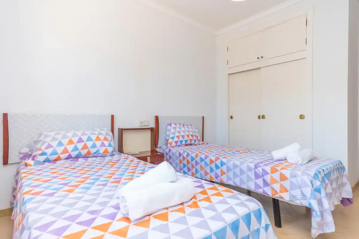 A bedroom with two beds dressed in colorful geometric-patterned bedding.