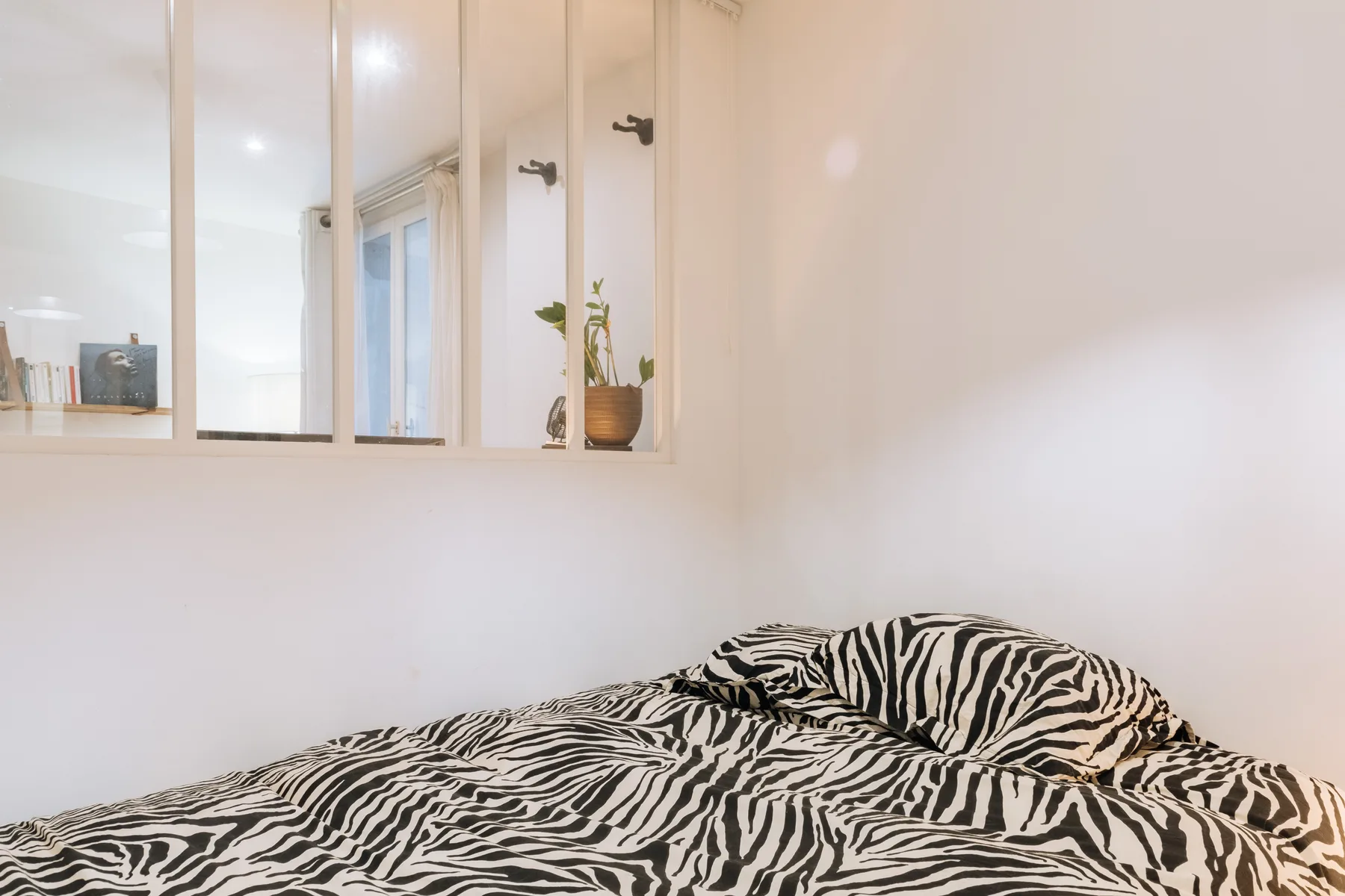 Un dormitorio con una cama cubierta con ropa de cama estampada en blanco y negro.
