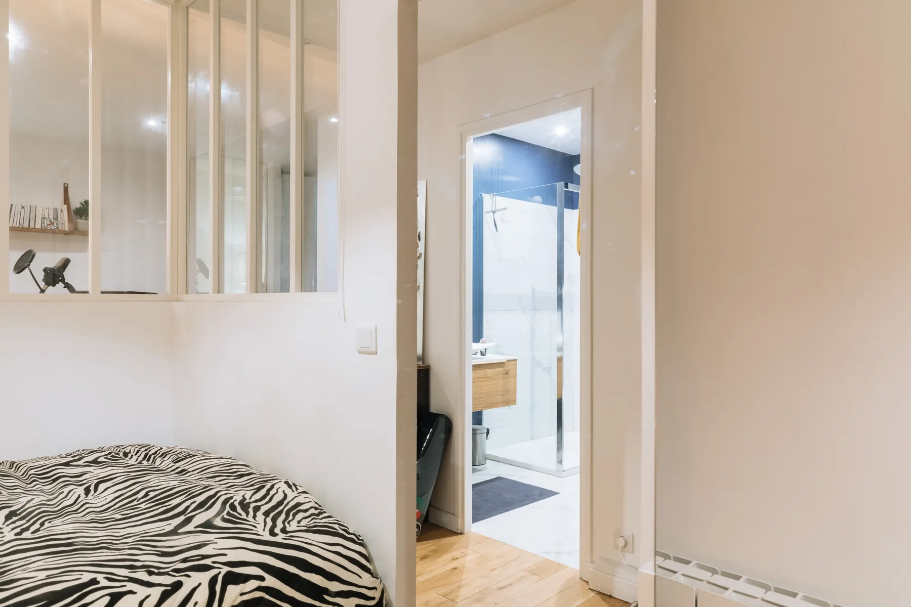 Dormitorio con ropa de cama estampada junto a una puerta abierta al baño.