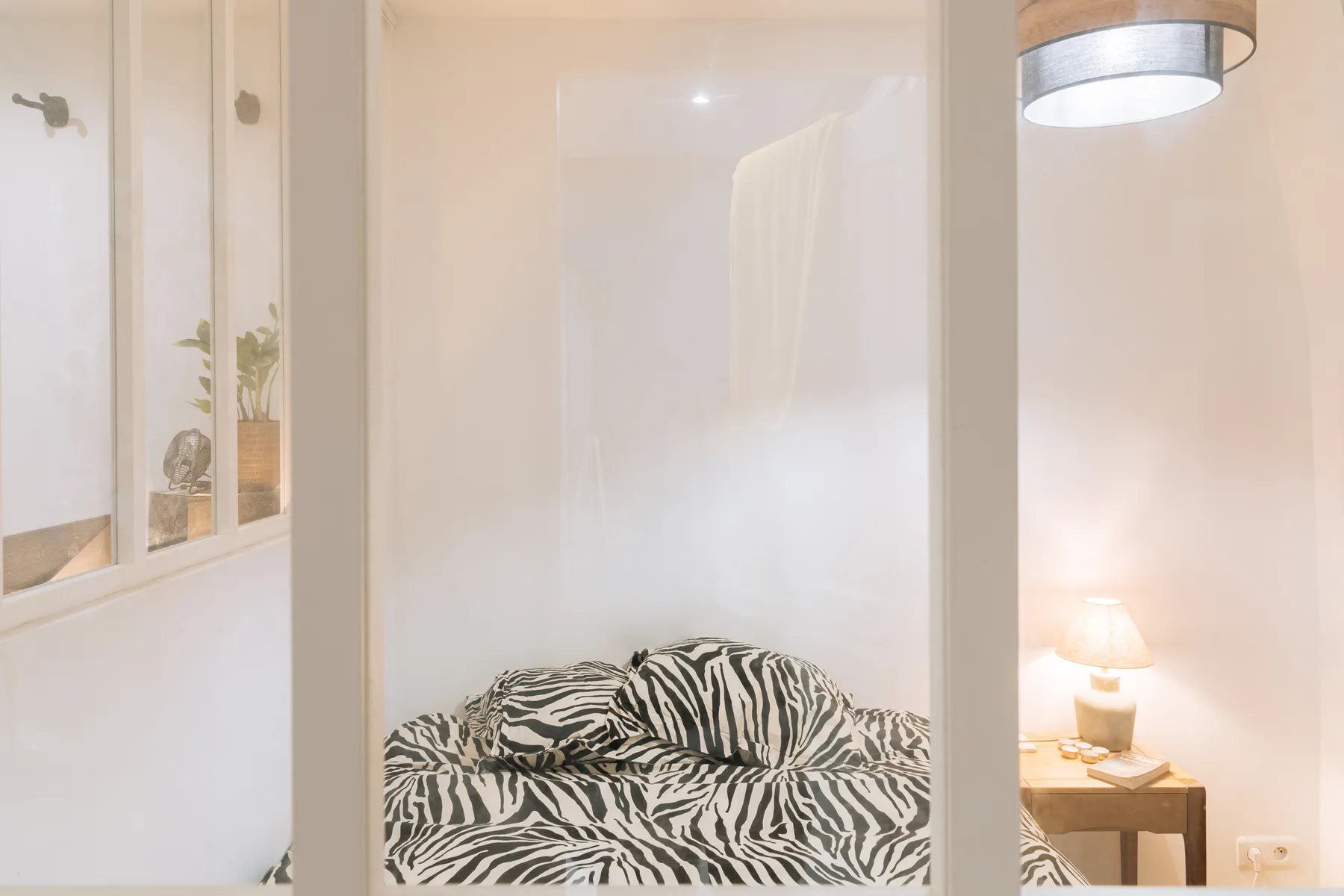 Dormitorio con una cama cubierta por una llamativa colcha estampada en blanco y negro.