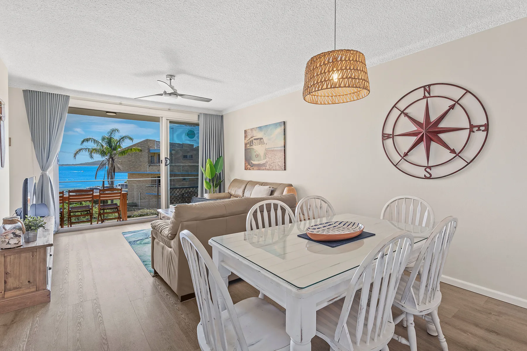 A living and dining area opens onto a balcony overlooking the ocean.
