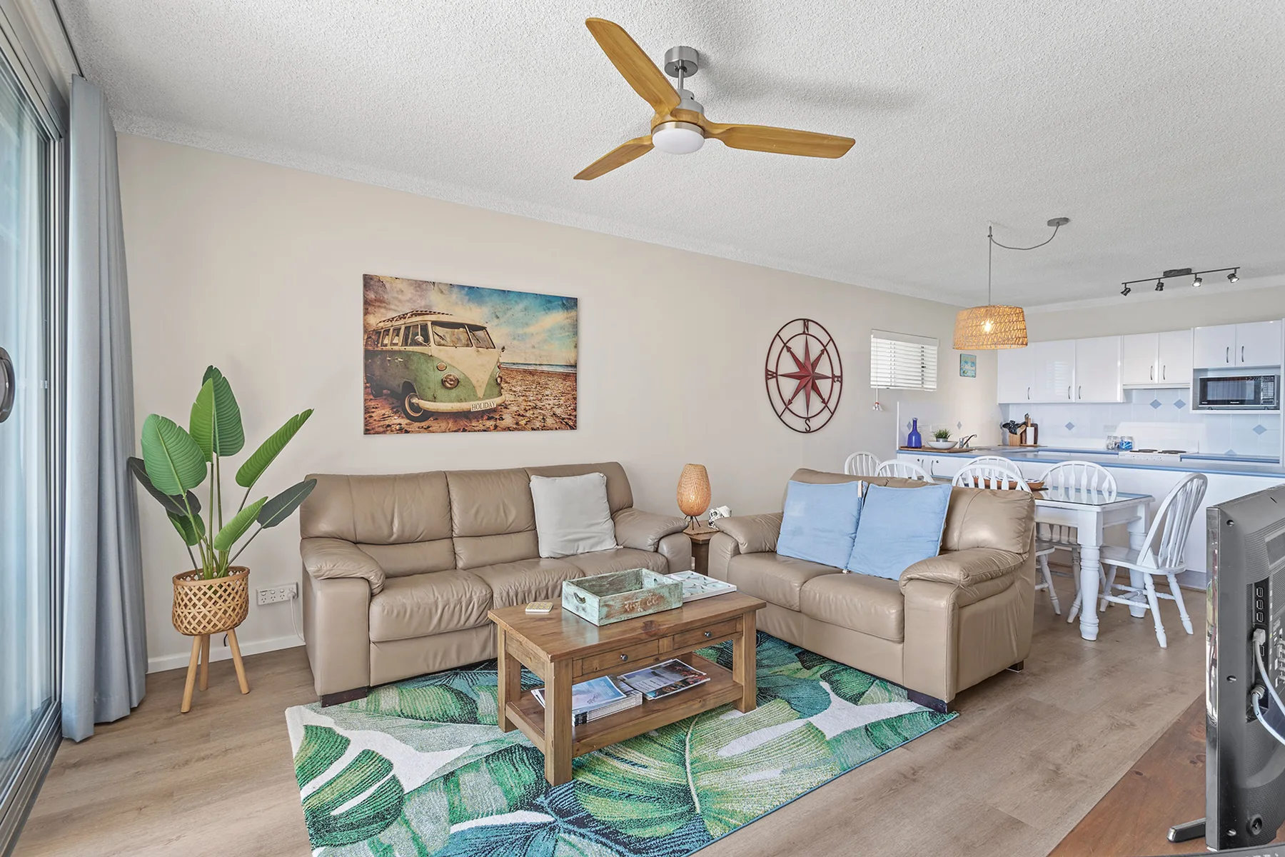 A bright living room with seating beside an open kitchen and dining area.