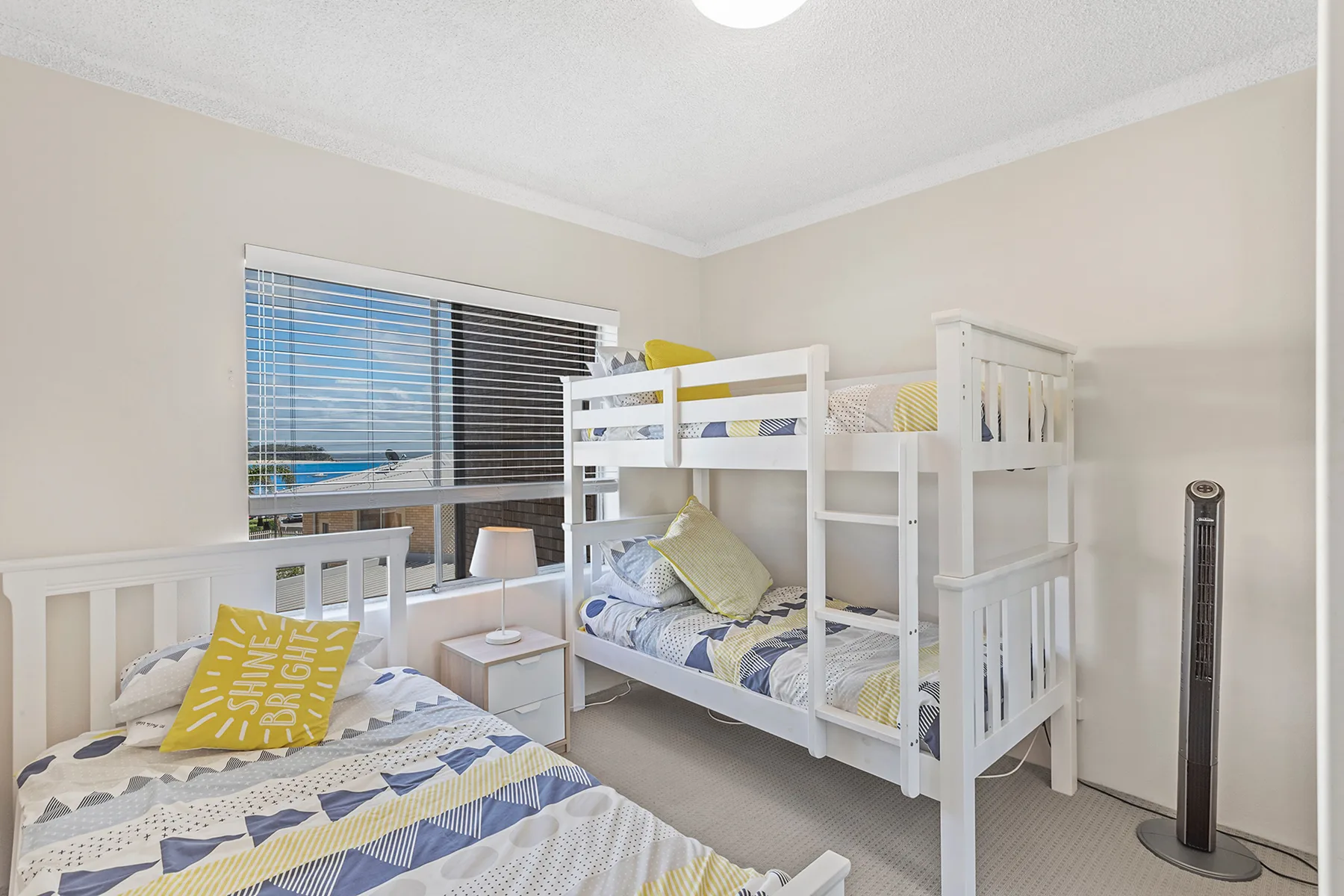 A bedroom with bunk beds, a single bed, and a window overlooking the water.