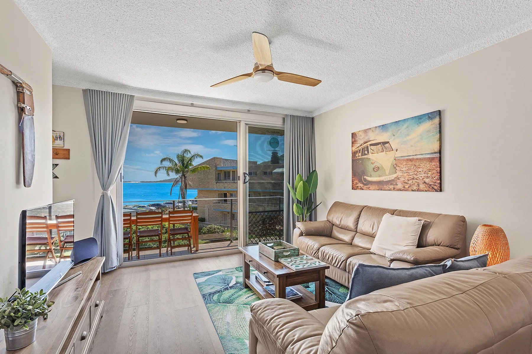Living room with seating around a coffee table beside sliding glass doors.