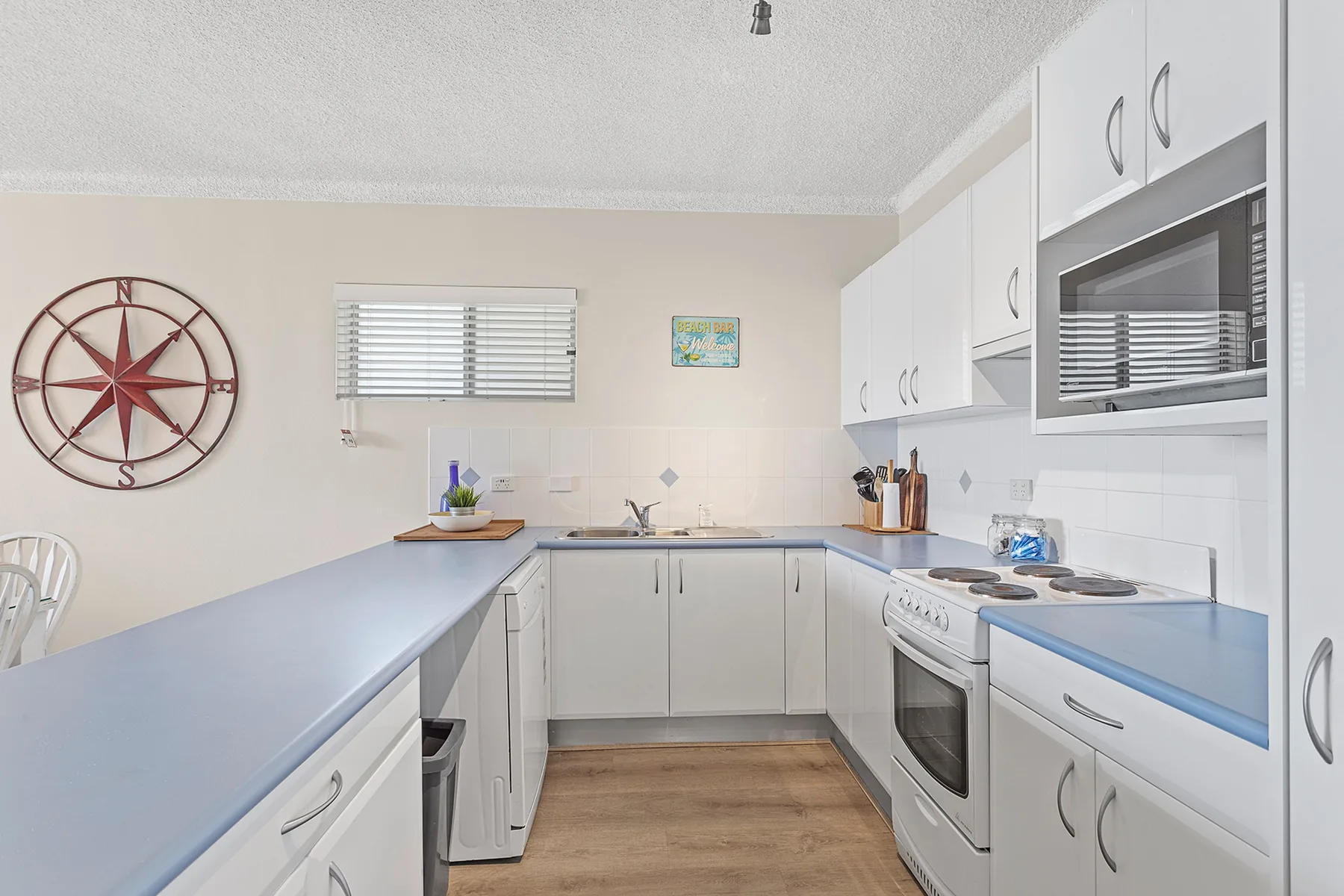 A bright kitchen with white cabinets, blue countertops, and a cooking range.