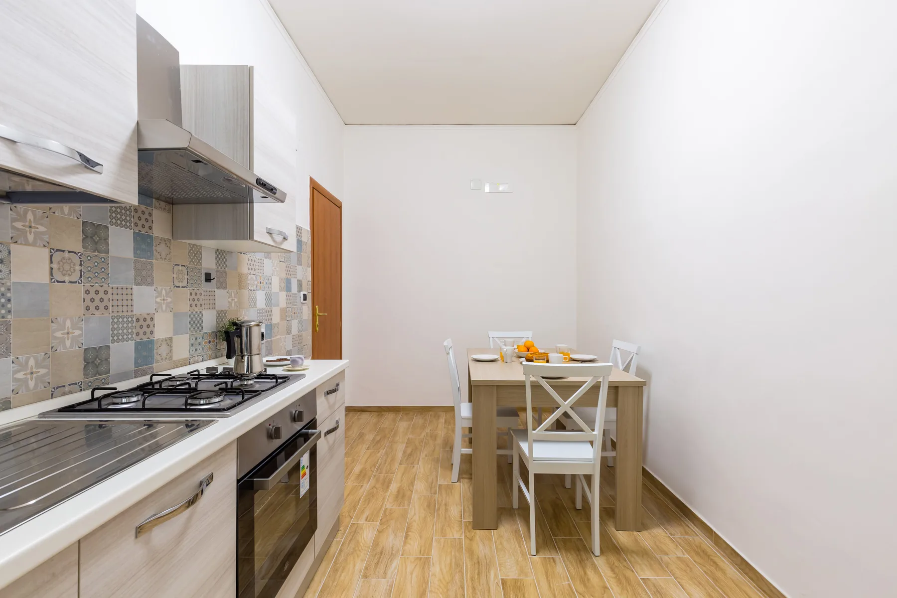 A bright kitchen with a dining table and patterned backsplash.