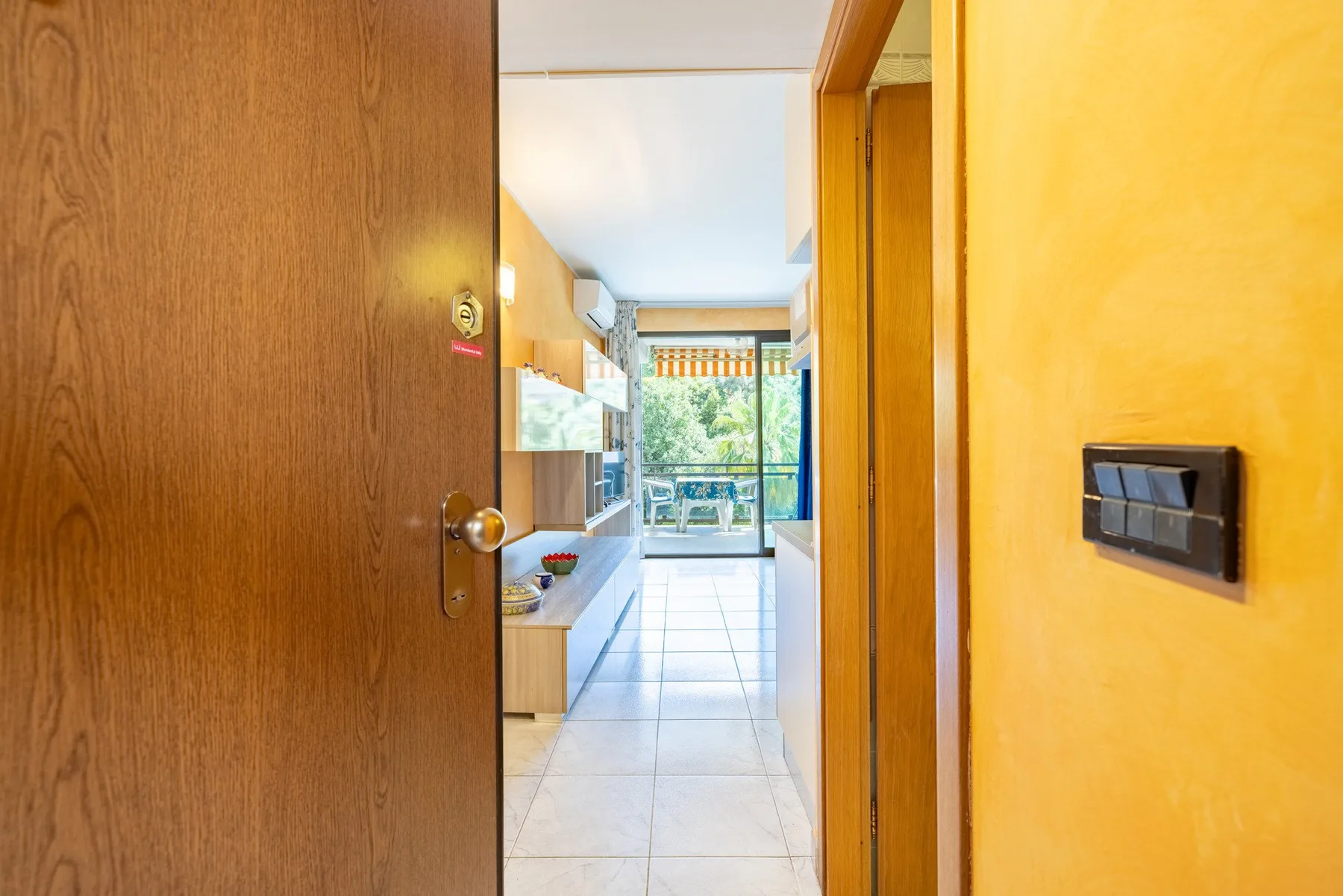 Un pasillo pasa junto a una zona de cocina y conduce a una ventana luminosa.