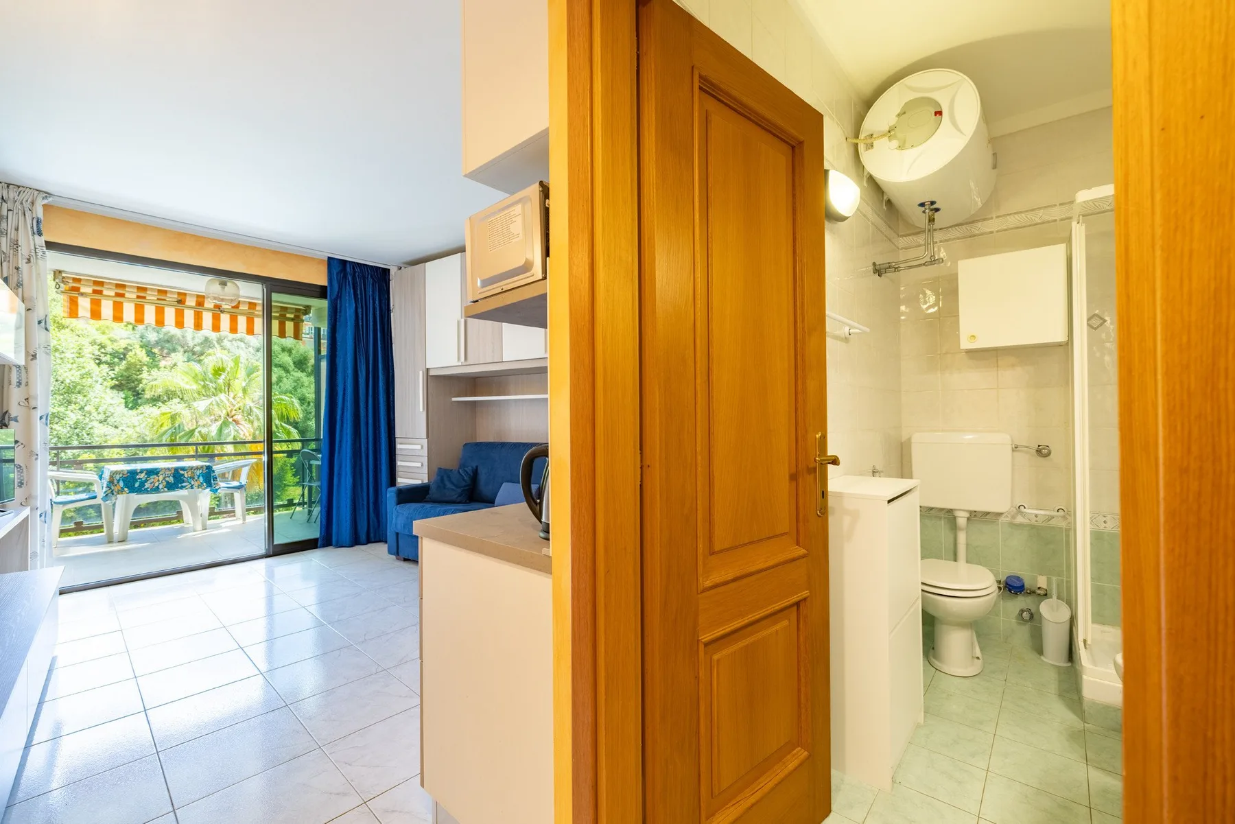 Interior de un apartamento compacto con cocina pequeña, zona de estar y baño.