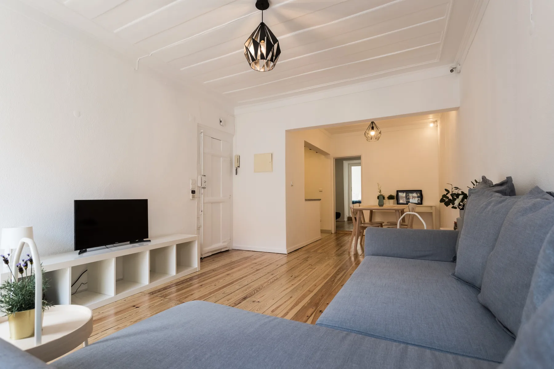 Una sala luminosa con televisor, asientos y un comedor al fondo.
