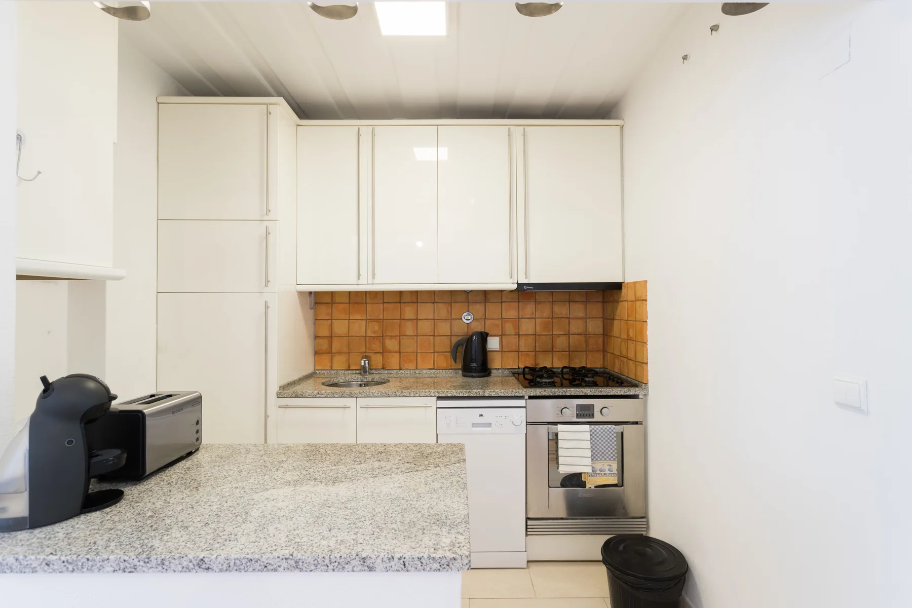 Una cocina luminosa con armarios blancos y un salpicadero de azulejos.