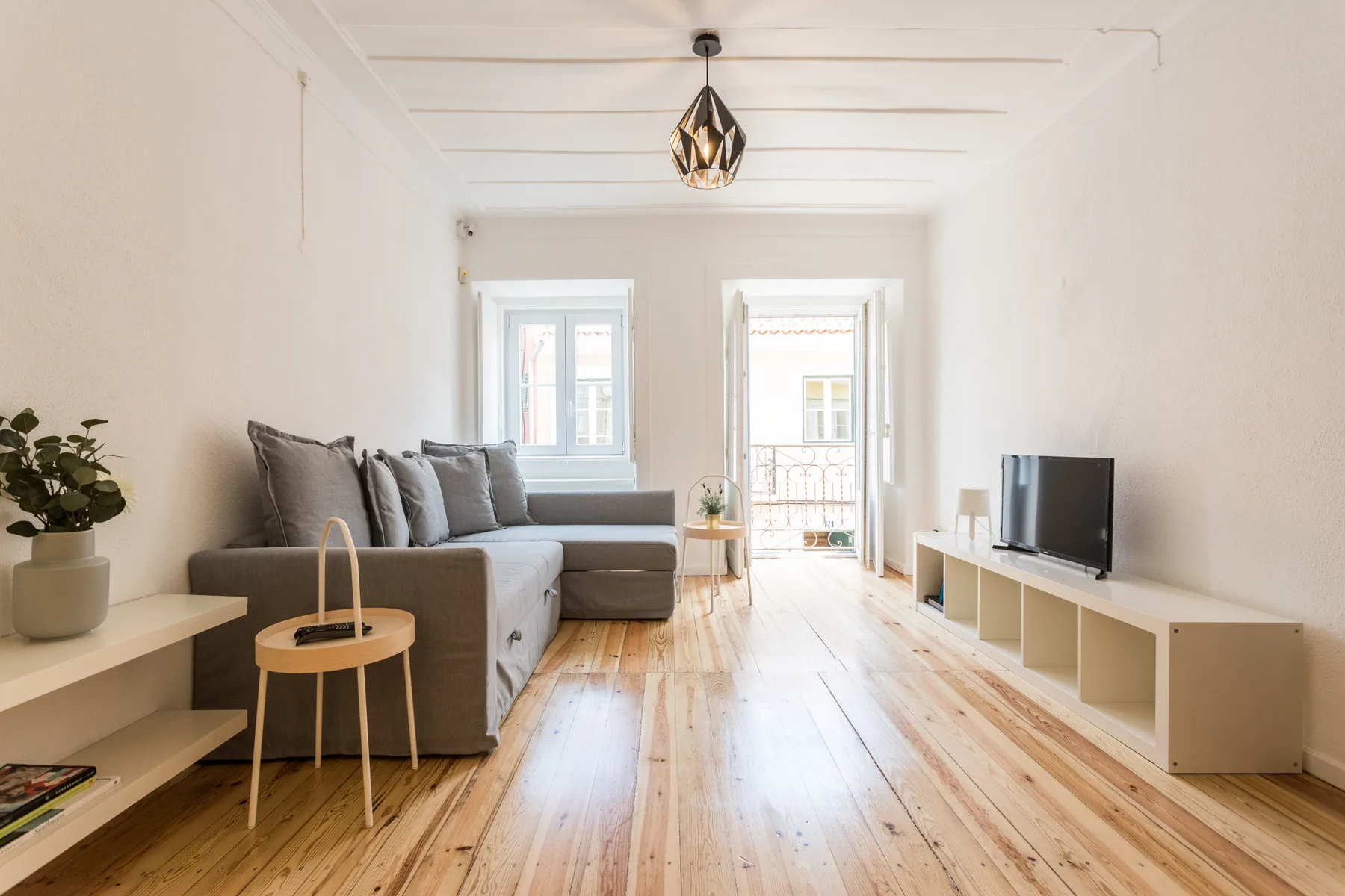 Una sala luminosa con asientos, un televisor y ventanas altas.