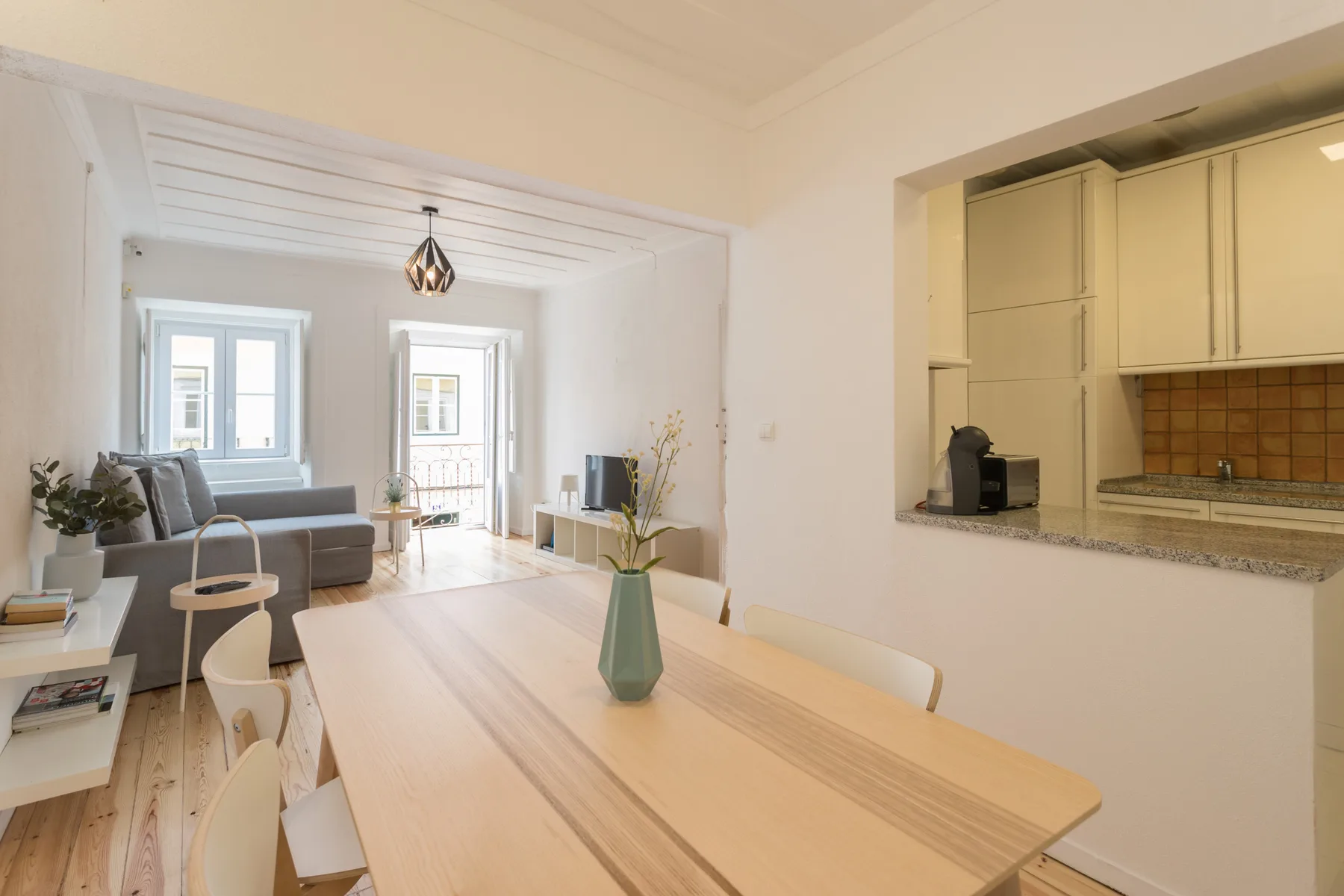Un comedor luminoso da a una sala de estar con ventanas grandes.
