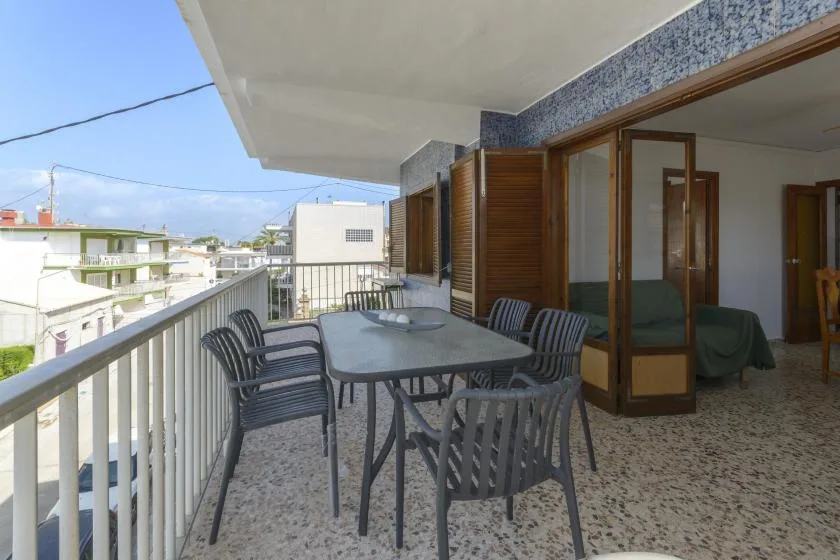 A balcony dining area with a table, seating, and views of nearby buildings.