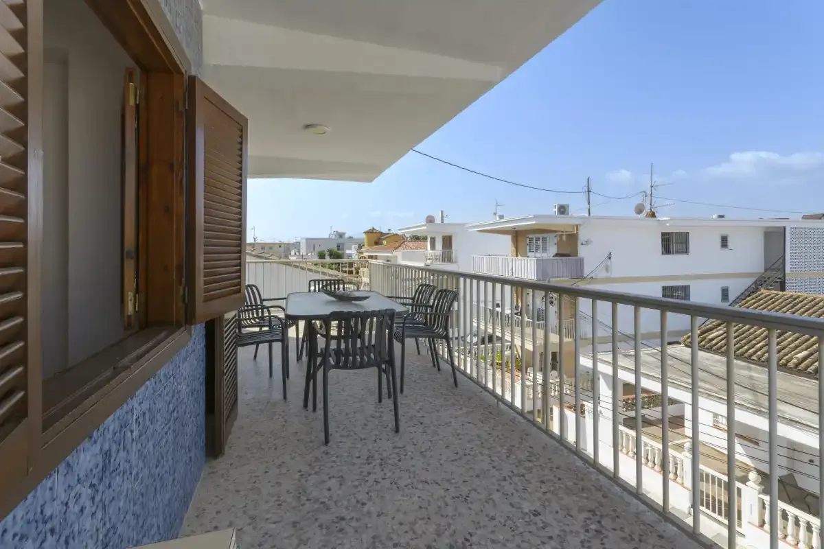 A covered balcony with outdoor seating overlooks nearby buildings.