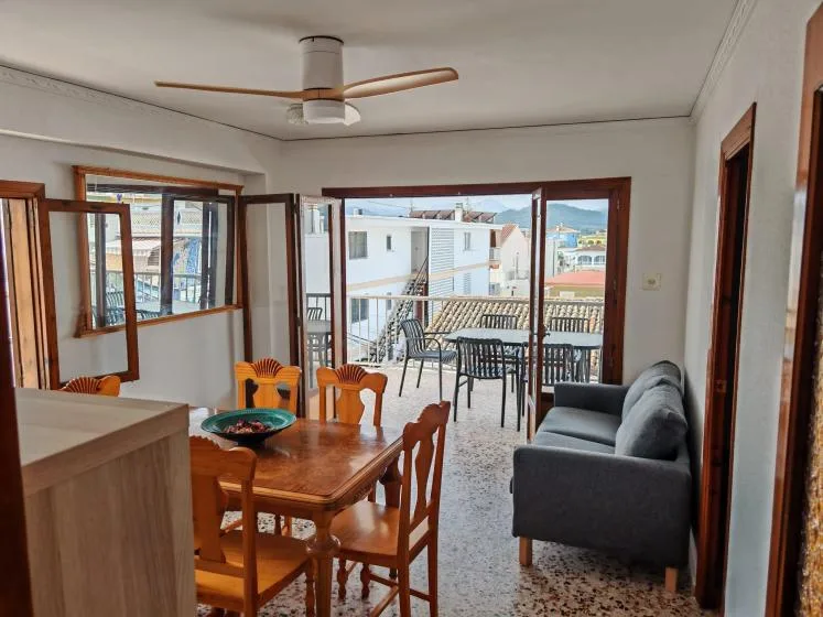 A dining and living area opens onto a balcony with outdoor seating.
