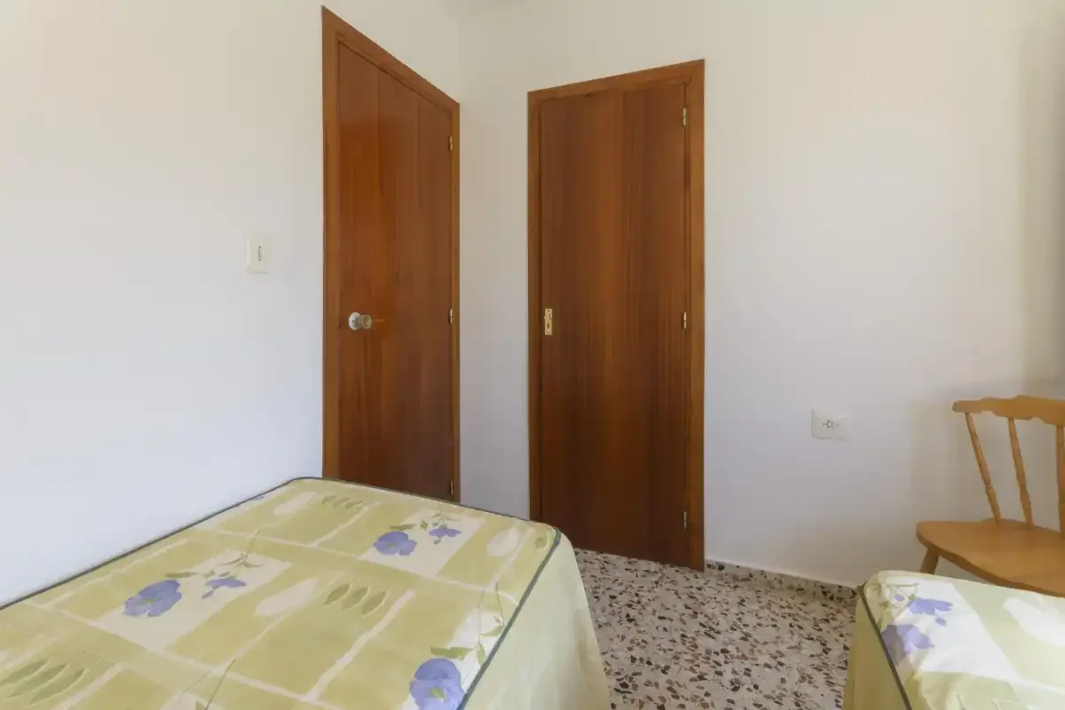 A bedroom with two wooden doors and beds covered in patterned bedding.