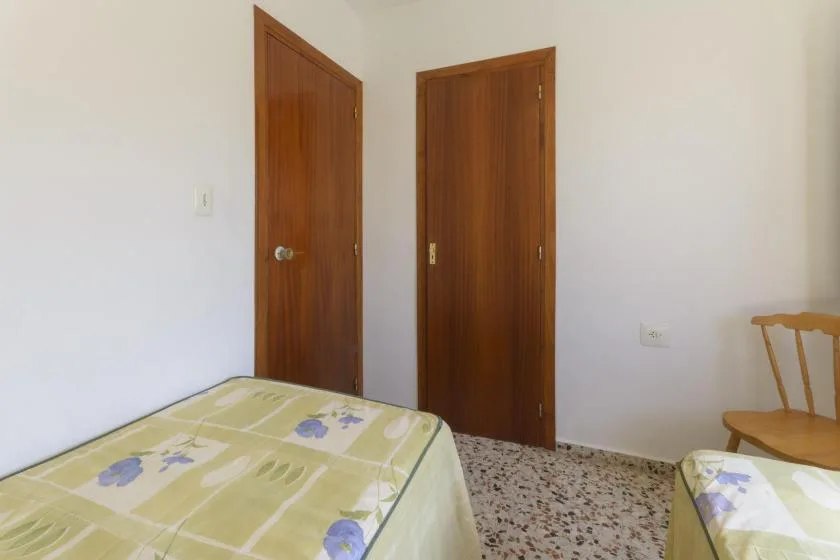 A bedroom with two wooden doors and beds covered in patterned bedding.