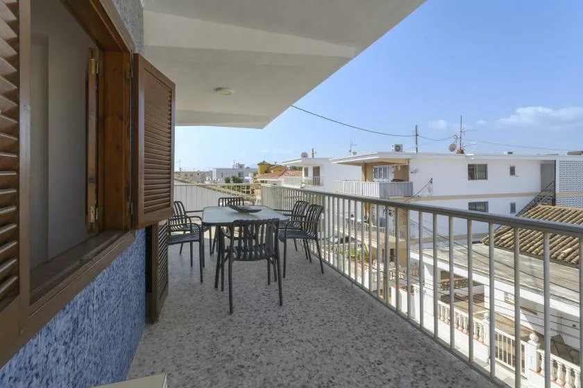 A covered balcony with outdoor seating and a railing overlooks nearby buildings.