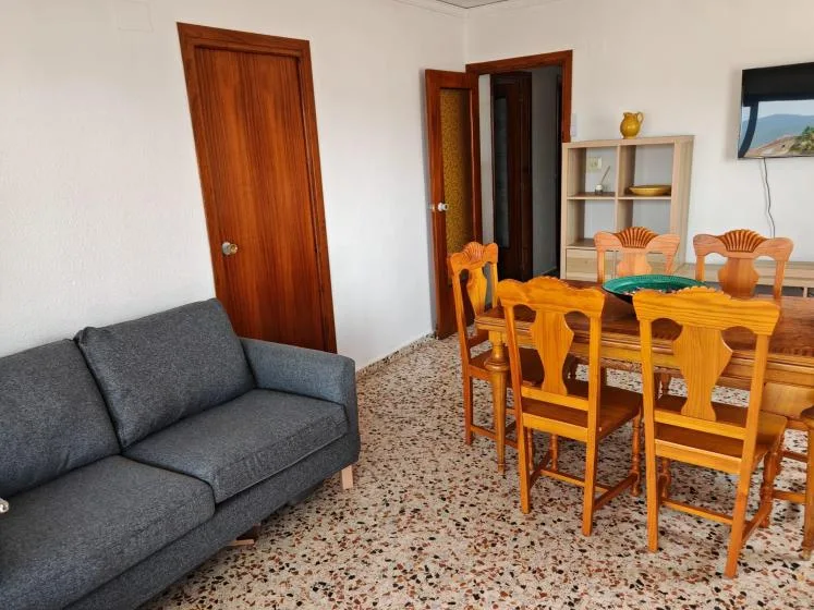 A living and dining area with a gray sofa, wooden table, and chairs.