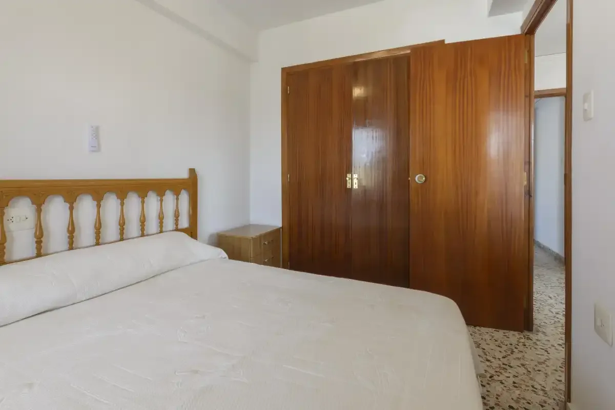 A bedroom with a bed and wooden wardrobe.