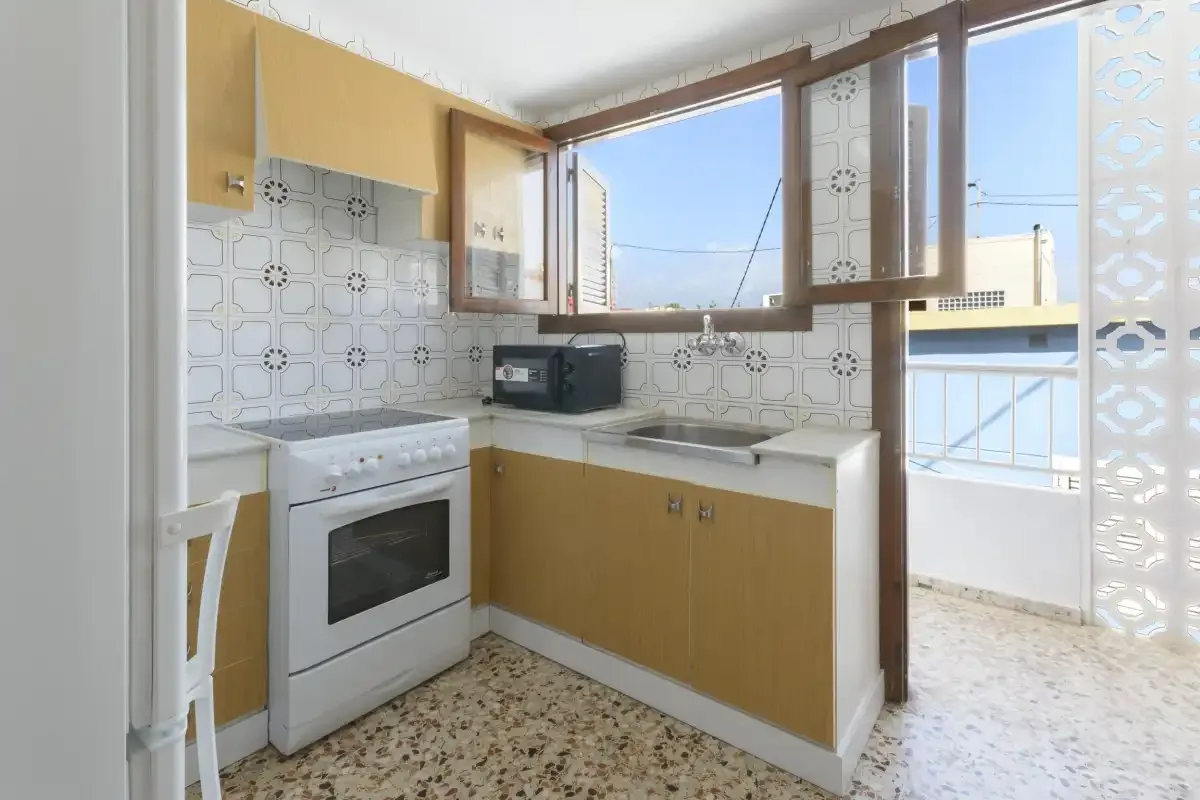 A bright kitchen with wood cabinets, a tiled backsplash, and a large window.