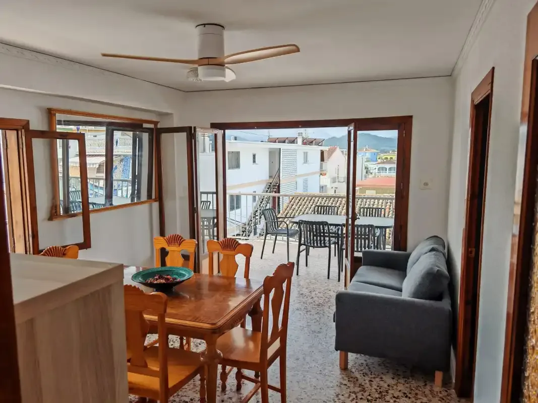 A dining and living area opens onto a balcony with outdoor seating.