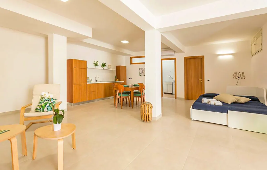 A bright open room with a dining area, kitchenette, and bed.