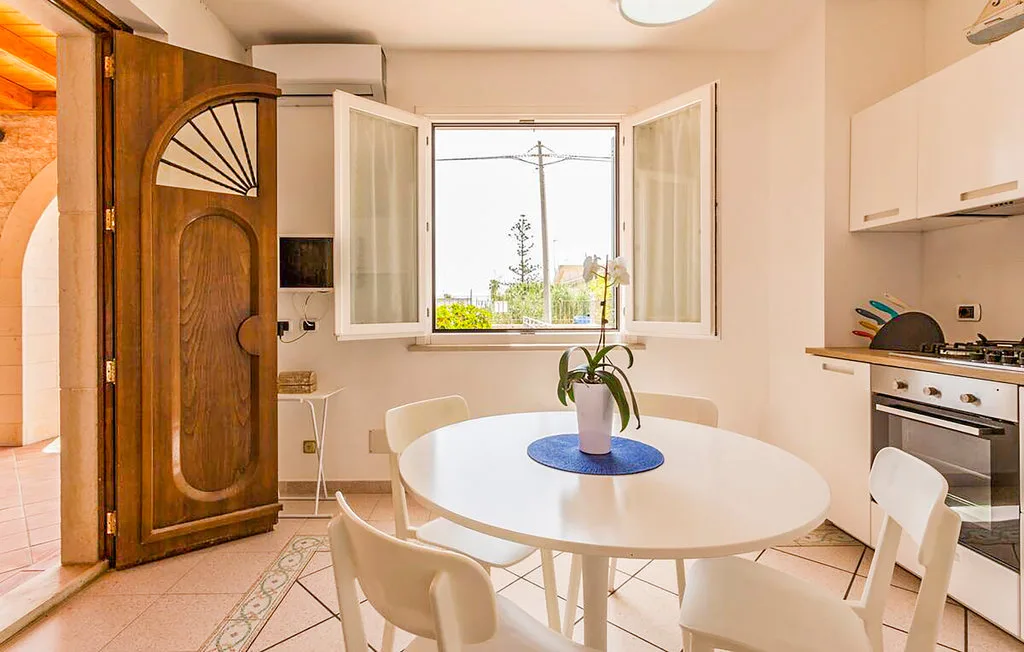 A bright dining area with a round table beside a window and kitchen.