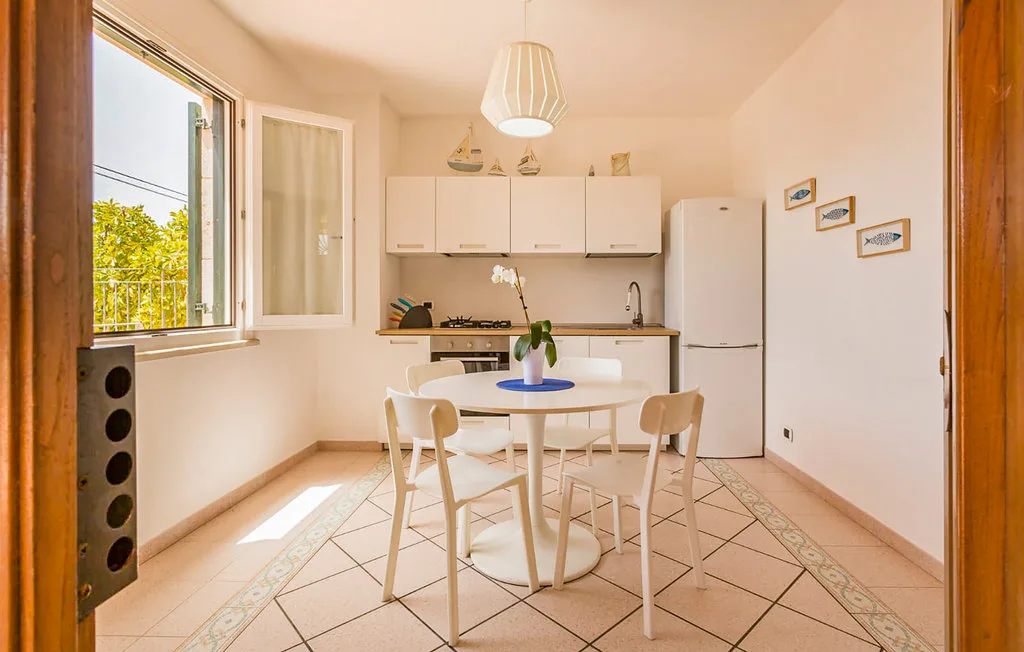 A bright kitchen and dining area with a round table beside an open window.