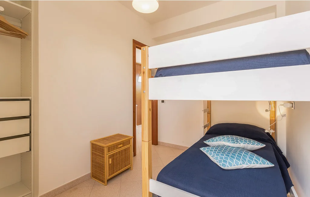 A bedroom with a bunk bed and a small cabinet beside it.