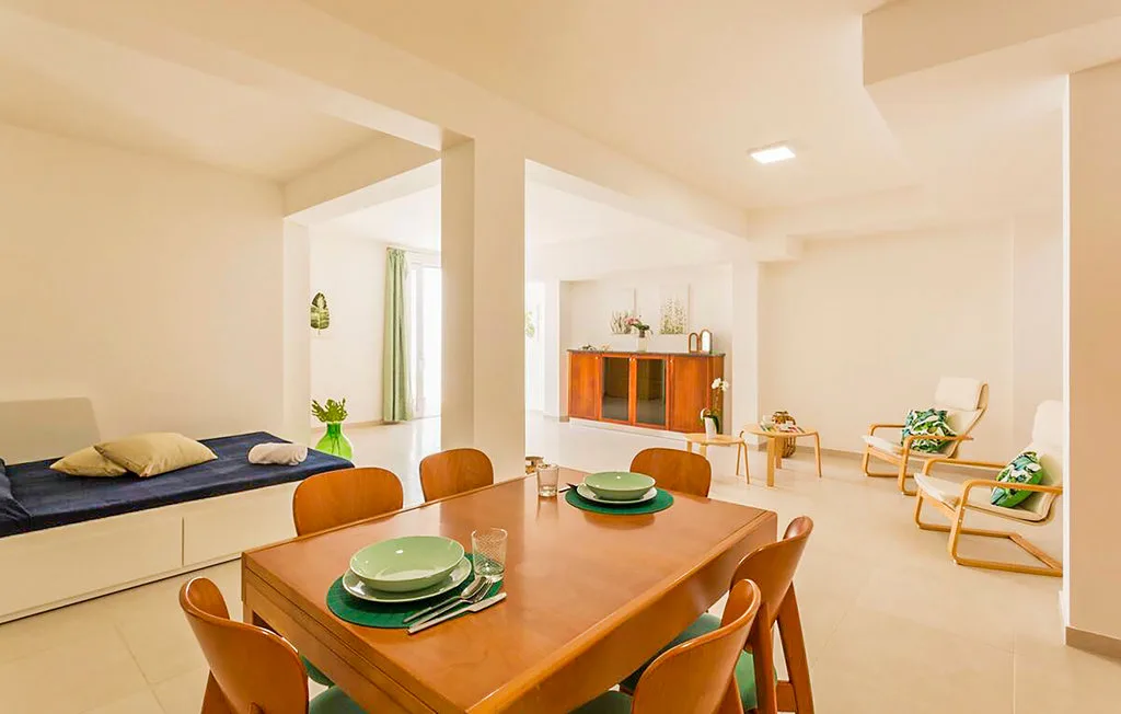 A bright dining area with a wooden table and seating beside a lounge nook.
