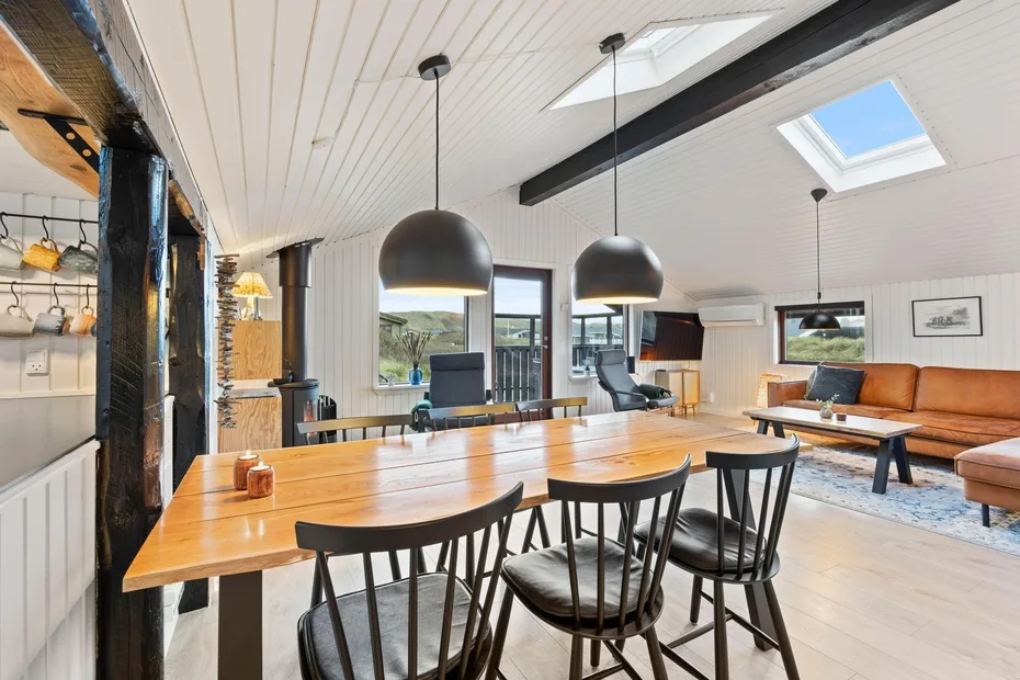 Un espacio abierto de comedor y sala tiene una mesa larga de madera y asientos.