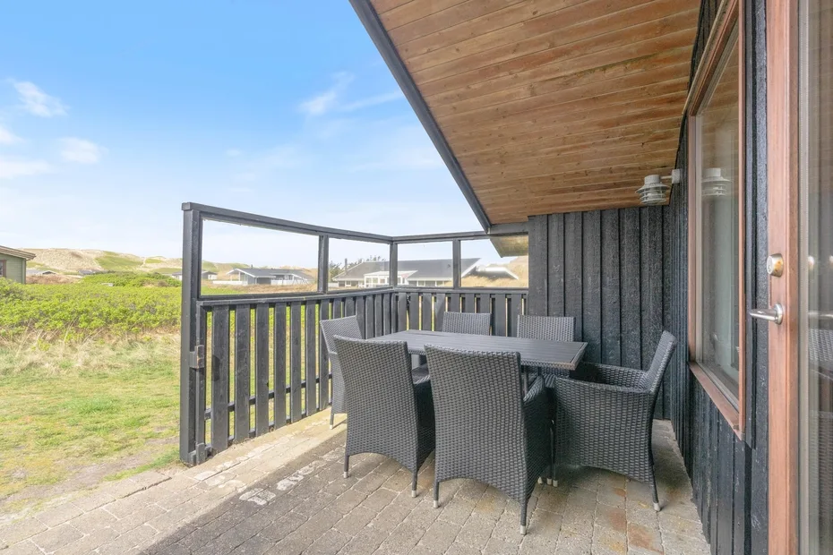 Una terraza amueblada con mesa y asientos junto a una pared exterior oscura.
