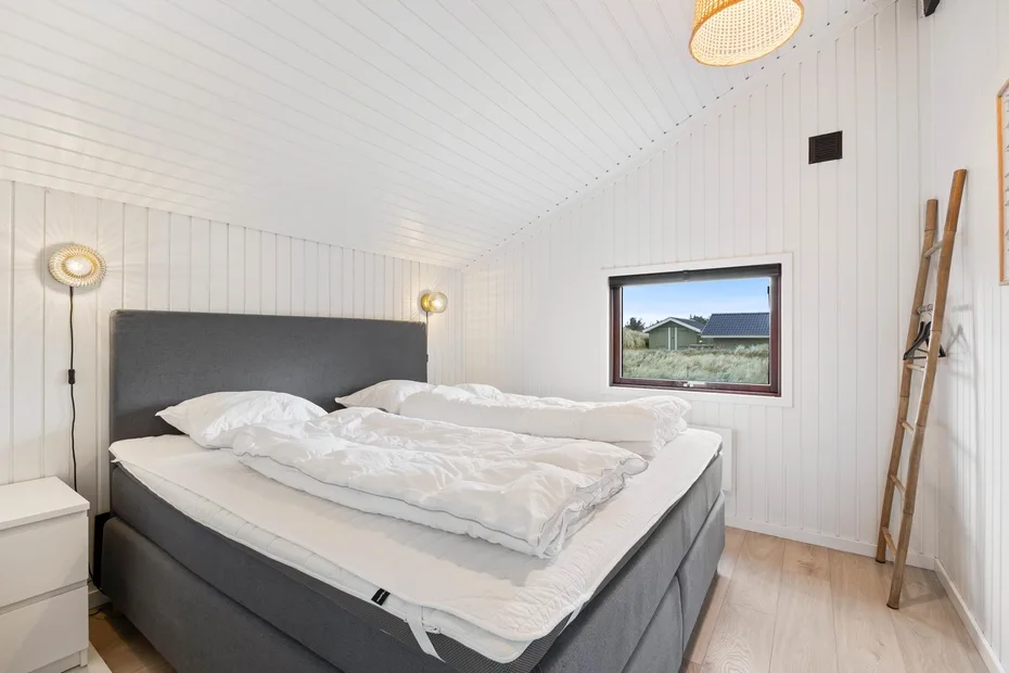 Un dormitorio con una cama grande vestida con ropa de cama blanca y una ventana.