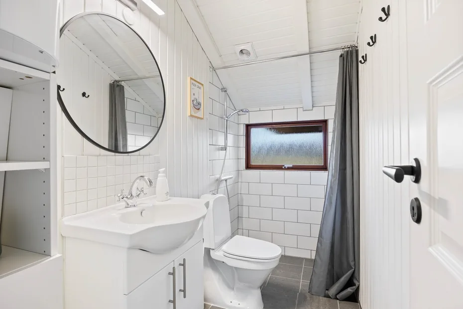 Baño luminoso con lavabo, inodoro y cortina de ducha.
