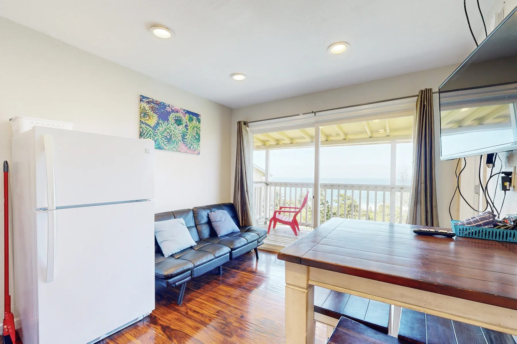 A bright living area with seating beside large windows overlooking a balcony.
