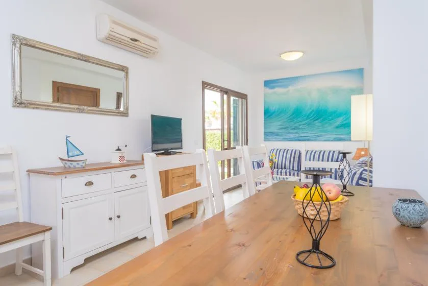 Una sala luminosa con una mesa de comedor de madera y un mural colorido del océano.