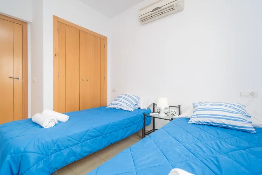 Un dormitorio con dos camas cubiertas con ropa azul y una mesita de noche.