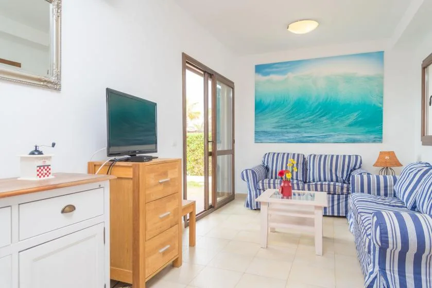 Una sala luminosa con asientos de rayas azules y un gran cuadro de olas.