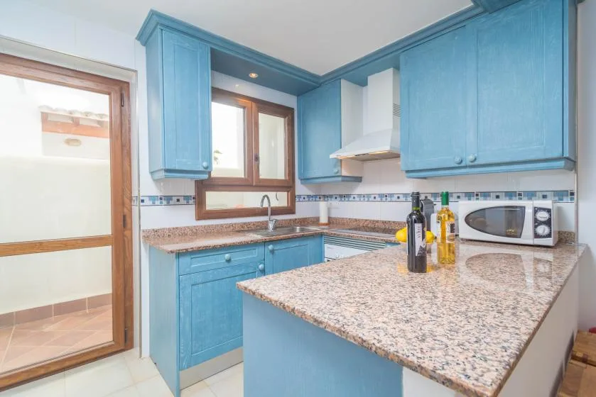 Una cocina luminosa con gabinetes azules, una isla y un microondas.
