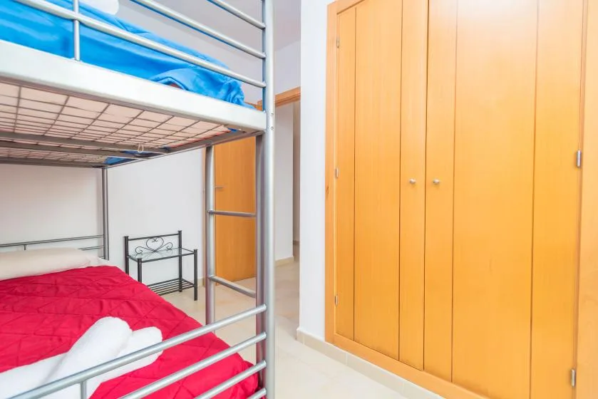 Un dormitorio con una litera de metal y un armario grande de madera.