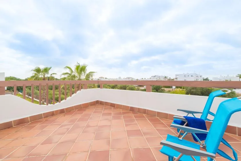 Una terraza enlosada con asientos azules y vistas a palmeras.