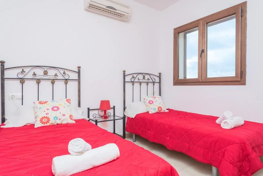 Un dormitorio con dos camas cubiertas con colchas rojas.
