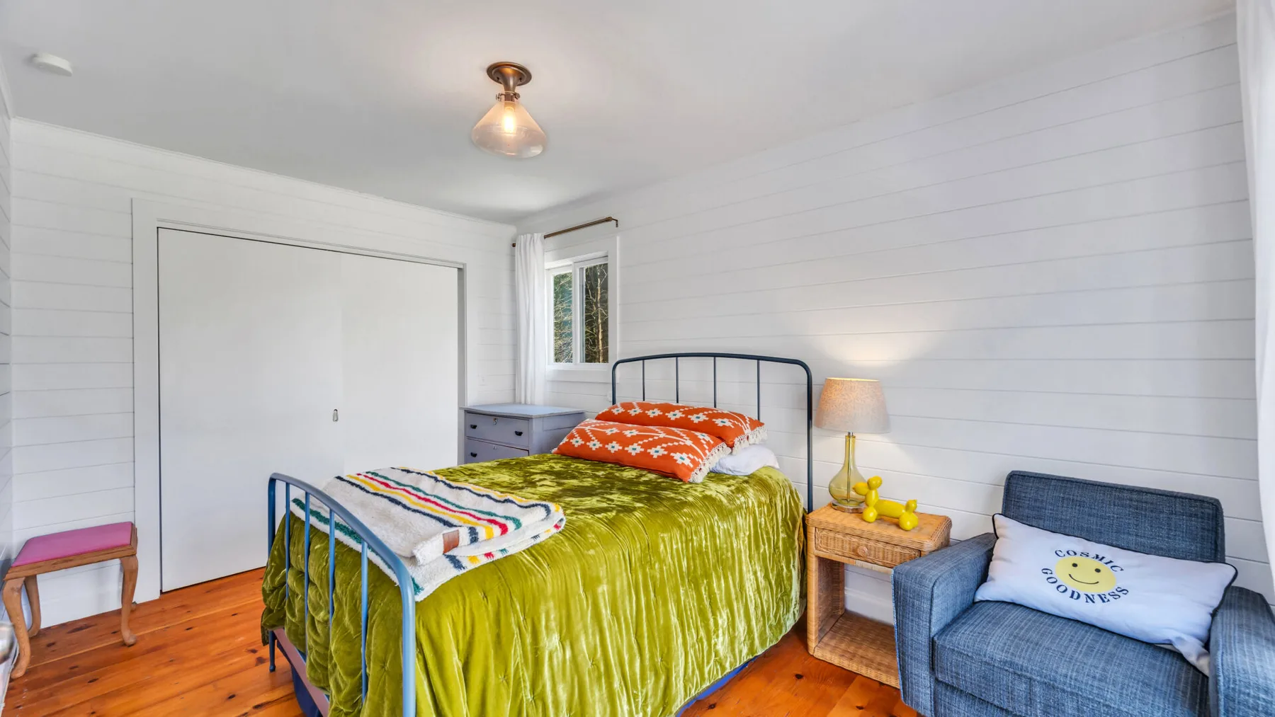 Un dormitorio con una cama, una mesita de noche y un sillón azul.