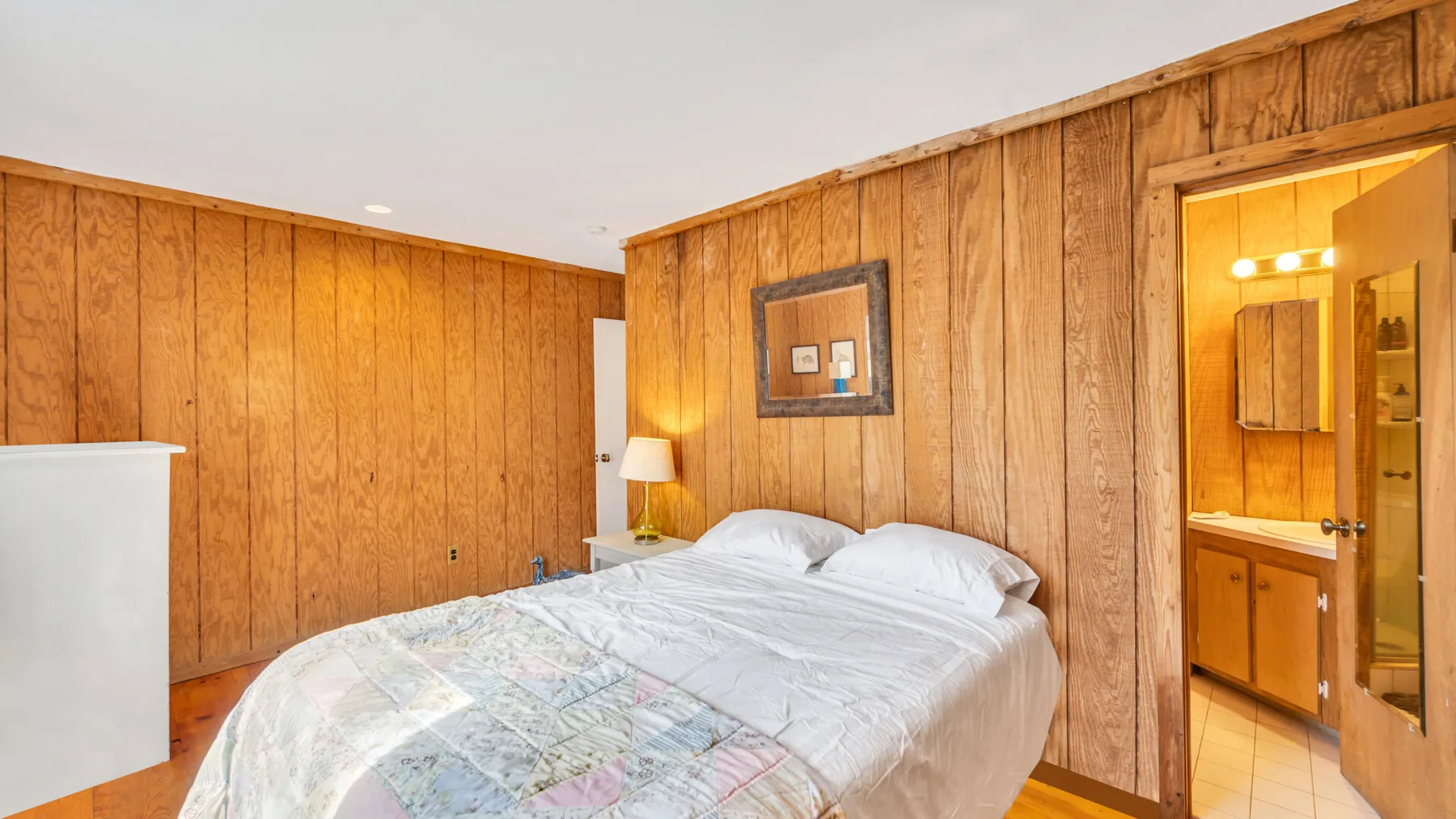 Un dormitorio con una cama y un baño visible a través de la puerta abierta.