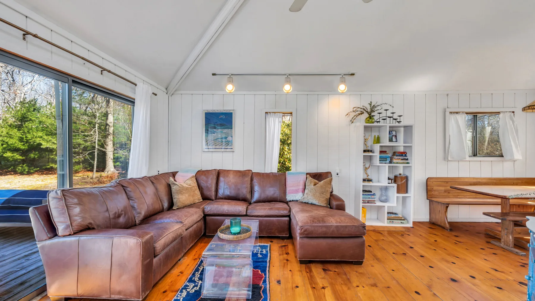 A bright living room with brown seating, a wooden coffee table, and large windows.