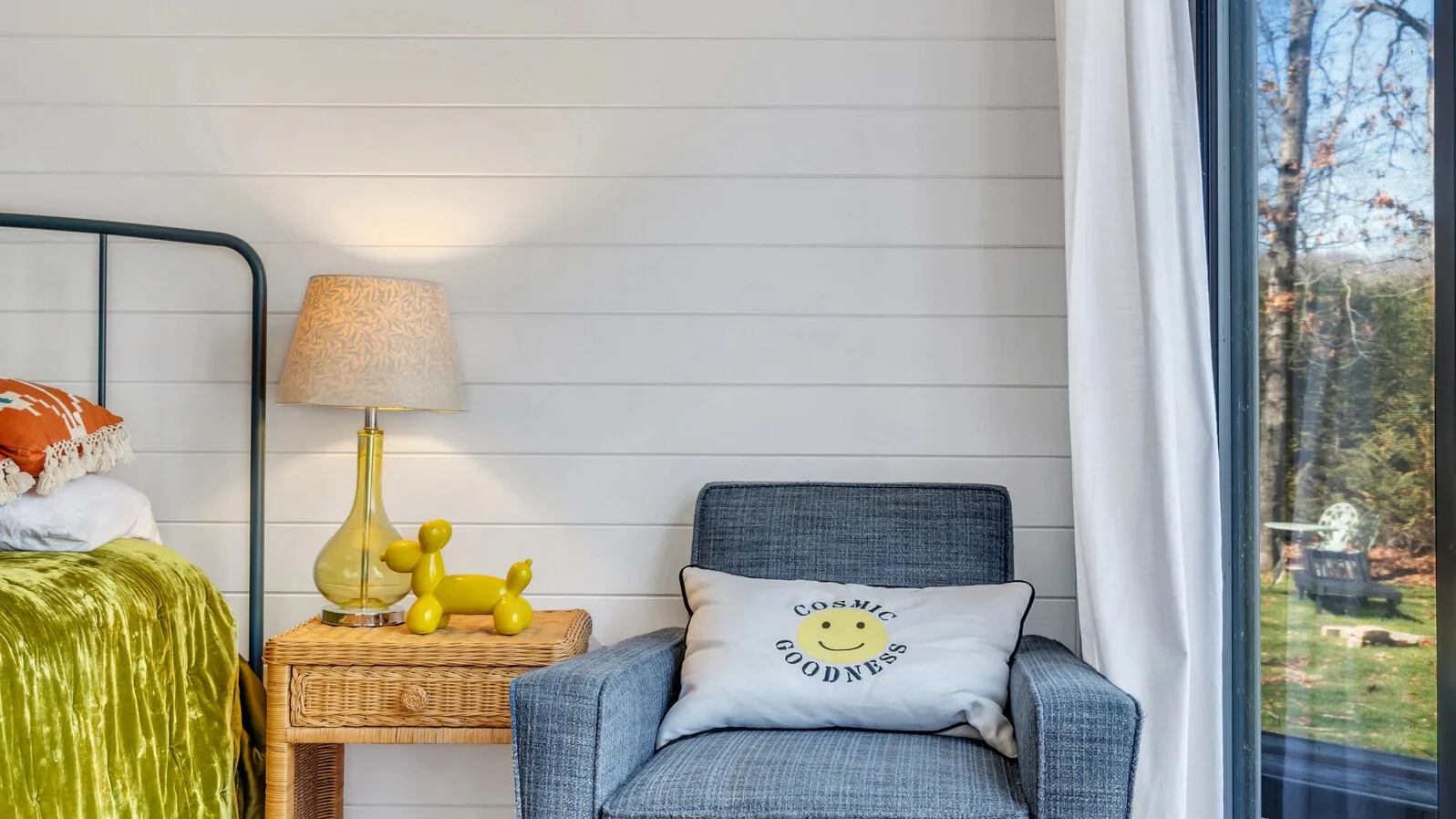 Una zona de descanso junto a la cama, con un sillón y una ventana.