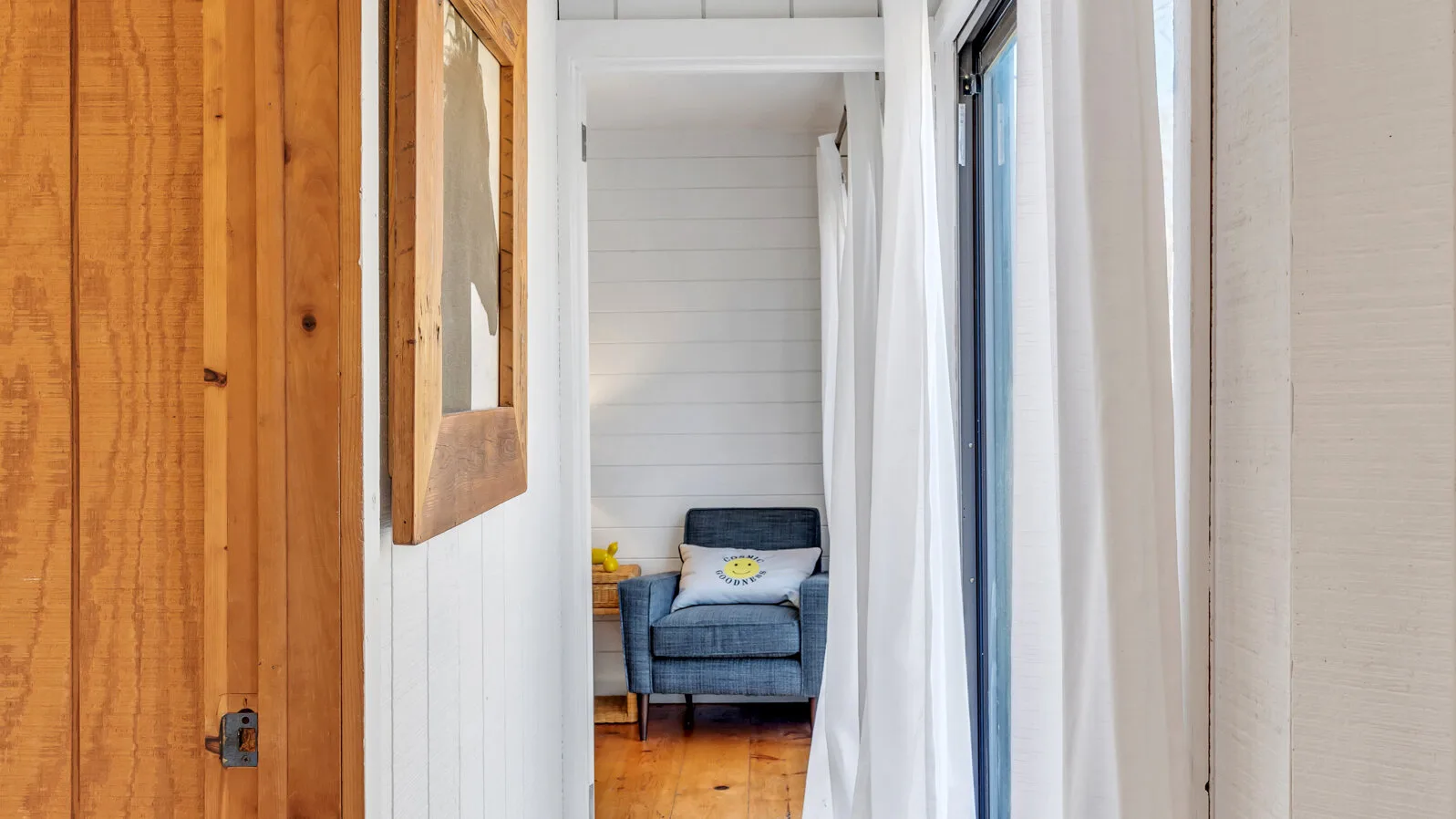 Un pasillo interior estrecho da a una pequeña zona de estar con un sillón azul.